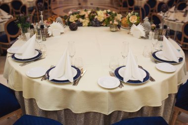 Çok güzel organize edilmiş bir etkinlik. Konuklar için yuvarlak masa ziyafeti, boş tabaklar, bardaklar, çatallar ve peçetelerle süslenmiş yuvarlak masa. Zarif bir yemek masası.