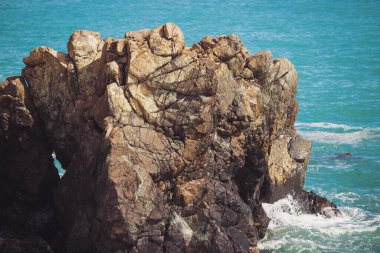 Mavi denizde taşlar, kayalık plajlar, yazın günbatımında dalgalar Liguria, İtalya 'da. Tropikal arka plan. Şeffaf gök mavisi su ve taşlar.
