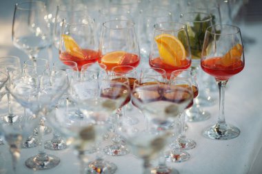 Nane, tekila, martini, votka ve diğer renkli mojito kokteyllerinden oluşan güzel bir sıra açık hava etkinlik partisinde yemek masasında. Yaz içkileri, düğün, parti.