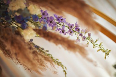 Çiçekler boho tarzında, otlu, yeşillikli, yumuşak odaklı. Kırsal dekorasyon, kırsal tasarım. Güllerle ve diğer mor yabani bitkilerle bezenmiş çiçekler.. 