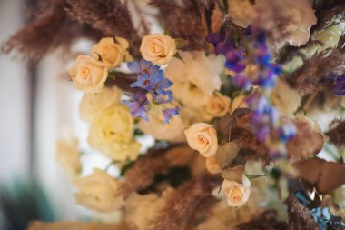 Çiçekler boho tarzında, otlu, yeşillikli, yumuşak odaklı. Kırsal dekorasyon, kırsal tasarım. Güllerle ve diğer mor yabani bitkilerle bezenmiş çiçekler.. 