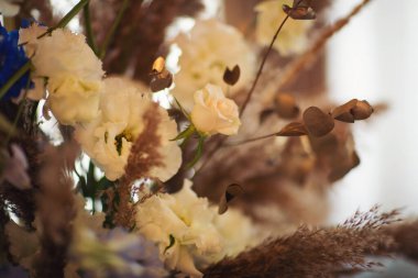 Çiçekler boho tarzında, otlu, yeşillikli, yumuşak odaklı. Kırsal dekorasyon, kırsal tasarım. Güllerle ve diğer mor yabani bitkilerle bezenmiş çiçekler.. 