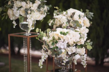 Çiçeklerin açık havasında mumlarla yapılan düğün töreni. Yeni evliler için nazik ve güzel bir düğün dekoru. Çeşitli yeşilliklerden büyük ve güzel bir buket çiçek..