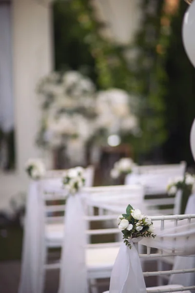 stock image Ceremony in the bosom of nature. White chairs with flowers set in the grass. white chairs lined up for an event accompanied by a bouquet of white flowers.