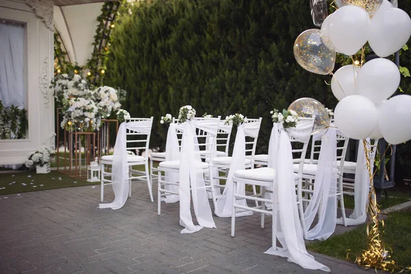 Ceremony in the bosom of nature. White chairs with flowers set in the grass. white chairs lined up for an event accompanied by a bouquet of white flowers.