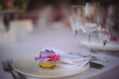 Ballı bonniere düğün masasında servis edilecek. Küçük bal kavanozlarının düğün hediyeleri. Düğün davetlileri için tabakta bir hediye. Kurdeleli ve kağıt kelebekli küçük bal şişesi.. 