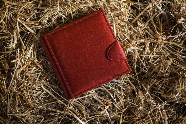 intage concept of empty cover of brown leather book frame on yellow hay background texture. Photobook on straw. Wedding photobooks in brown leather binding. Wedding photo book, album family album.