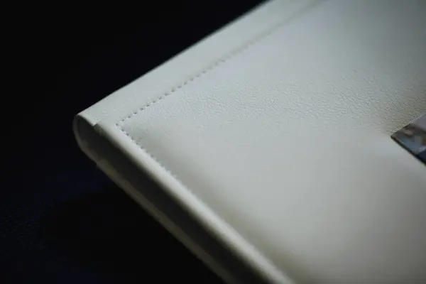 Details of a beautiful leather bound books with white blank cover. The texture of the cover of a photobook made of genuine leather. Wedding photobook. Family photo album. Memory book with leather cover. Detail of photoalbum with hard leather cover.