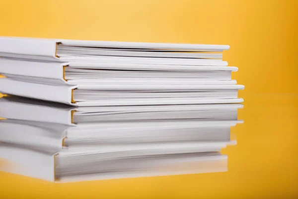 Stack of White Books on yellow  Background. Close up photobook stacked. forefront of a group of books stacked. An abstract shot of a pile of books. Blank white stack of books.
