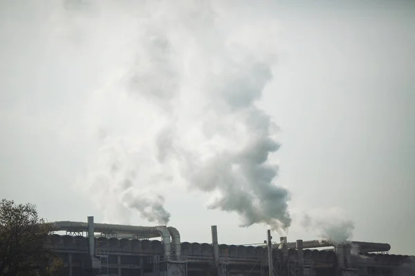 Smoke stack with smoke emission. Plant pipes pollute atmosphere. Industrial factory pollution, smokestack exhaust gases. Industry zone, thick smoke plumes. Climate change, ecology.