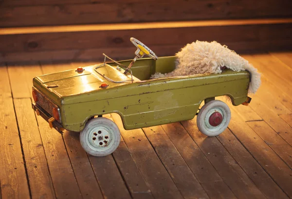 vintage model of toy car. Old rusty decorative car. Retro style green toy car in wooden room background.