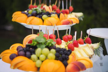 Büfe resepsiyonu meyveleri, şaraplar, şampanya. Düğün masasında meyve tabağı. Yemek kanapesi çeşitli taze meyveler, böğürtlenler ve narenciye. Tatil için meyveler. Etkinlikte restoran servisi.