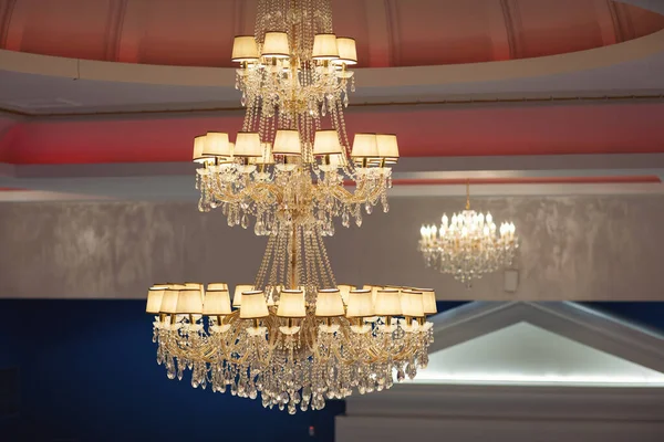 A contemporary chandelier, is a branched ornamental light fixture designed to be mounted on ceilings. Beautiful classic chandelier hanging on the ceiling, conical lampshades for the chandelier.