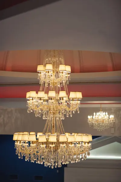 A contemporary chandelier, is a branched ornamental light fixture designed to be mounted on ceilings. Beautiful classic chandelier hanging on the ceiling, conical lampshades for the chandelier.