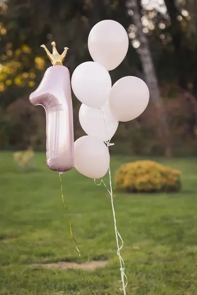 One year birthday decorations for beautiful girl. Girls style. A lot of balloons pink and white in park. Decor from the balloons with the figure 1. First birthday baloons.