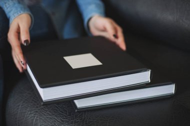 Dişi eller, yumuşak kumaşlı, siyah kaplı güzel bir kitabı kutuda tutuyor. Düğün fotoğrafları, aile albümleri. Gerçek deriden yapılmış bir fotobook 'un kapağının dokusu. Hediye için fotoğraflar