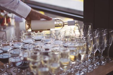 Düğün yemeği servisi. Evlilik kutlaması konsepti. Restoran ve bar alkol menüsü. Lüks içki. Açık hava ziyafeti. Piramit dekorunda kokteyller. Garson bir bardak şampanya getirmiş..