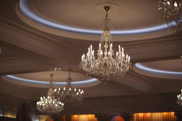 large round chandelier with crystals and candlesticks on the ceiling, retro style. Beautiful chandelier in luxury room shining. crystal chandeliers with lots of lights in a restaurant.