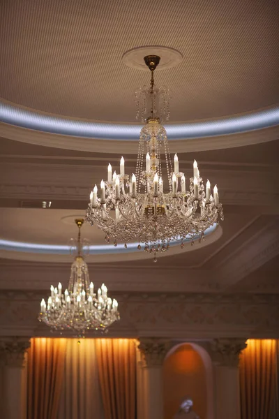 large round chandelier with crystals and candlesticks on the ceiling, retro style. Beautiful chandelier in luxury room shining. crystal chandeliers with lots of lights in a restaurant.