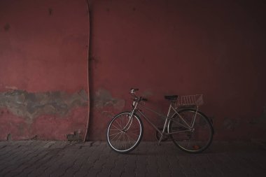 Kopya alanı olan eski duvarın yanında duran antika bir bisiklet. Araç. Nakliye aracı. Bisiklet. Bisiklet araçlarının eski şehirde seyahat etmesi kolaydır. Kırsal kesime park edilmiş bir bisiklet..