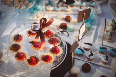 Bebek partisi, süslemeler ve mavi renkli pastalar. Tatlılar ve pasta masada parti için hazır. Muffinler, kekler, meyveler, şekerlemeler ve şekerlemelerle dolu güzel bir çikolata..