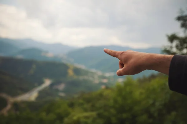El dağların üzerinde yön gösteriyor. Yürüyüş yapan bir turist, elini uzattı. El, dağdaki seyahat rotasına rehberlik etti. Seyahat et ve son tatilde dinlen. Yumuşak odak ve bulanıklık. 