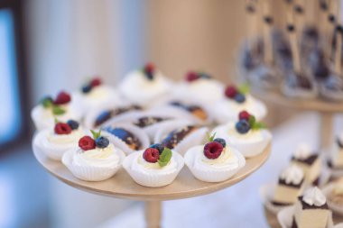 Çeşitli lezzetli tatlılar, kremalı kekler, böğürtlen, krem şanti, lokum, şenlikli dekor, tatlı bar, ikram. Yemek servisi. Lezzetli bir tatlı. Düğün ziyafeti masası. Tatlı büfede hamur işi