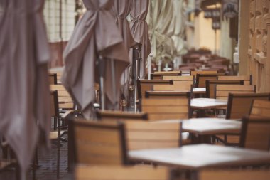 Şemsiyeler ve barın masaları. Kafe kafe restoranının terasında. Tahta sandalyeler ve masalar. Açık teras. Antika sandalyeleri ve masaları olan eski moda boş kafe terası. Çatı katı tarzı kafe.