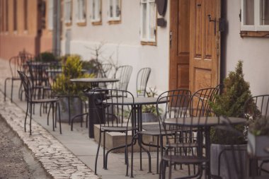 Kafe kafe restoranının terasında. Tahta sandalyeler ve masalar. Açık teras konsepti. Sığ odaklanma. Uzayı kopyala Antika sandalyeleri ve masaları olan eski moda boş kafe terası. Çatı katı tarzı kafe.