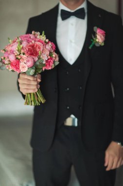 Zarif düğün süsleri. Bir etkinlikte gelin ve damat için düğün buketi. Elinde güzel bir buketle şık bir damat. Farklı çiçeklerden oluşan lüks bir düğün buketi..