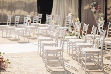 Doğanın bağrında bir tören. Çimlere çiçek konmuş beyaz sandalyeler. Beyaz sandalyeler, bir buket beyaz çiçekle birlikte bir etkinlik için dizildiler..