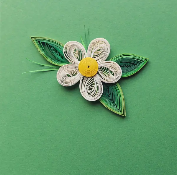 quilling card with white apple flower on green paper background. Spring flowers. Hand made of greeting cards in paper quilling technique. Handicraft at home. Hobby, home office.