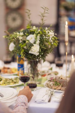 Şenlikli yemek için şık bir masa. Sandalyeler ve masa misafirler için, çatal bıçak takımı, yeşillik çiçekleri ve çanak çömlek ile servis ediliyor ve beyaz bir masa örtüsüyle kaplanıyor. Düğünde yemek servisi. Ziyafet..