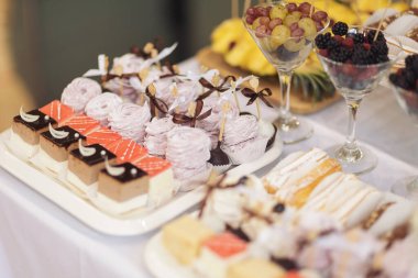 Kokteyl partisi ya da mağaza raflarında servis edilen pek çok küçük kek, şeker, meyve. Doğum günü veya düğün yemeği için çikolata. Yemek servisi. Lezzetli bir tatlı. Düğün yemeği masası.