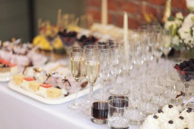 Parti ve tatil kutlaması konsepti. Restorandaki masada birçok bardak şampanya var. Düğünde yemek servisi. Lezzetli meyve aperatifleri, büfede tatlılar, içkiler, modern hesap.. 