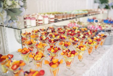 Büfe resepsiyonu meyveleri, şaraplar, şampanya. Düğün masasında meyve tabağı. Yemek kanapesi çeşitli taze meyveler, böğürtlenler ve narenciye. Tatil için meyveler. Etkinlikte restoran servisi.
