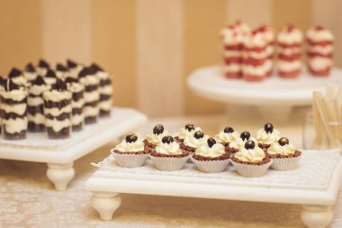 Kokteyl partisi için tabakta servis edilen pek çok küçük kek, tatlı ve meyve. Doğum günü veya düğün yemeği için çikolata. Yemek servisi. Lezzetli bir tatlı. Düğün ziyafeti masası. Partide meyveli çikolata