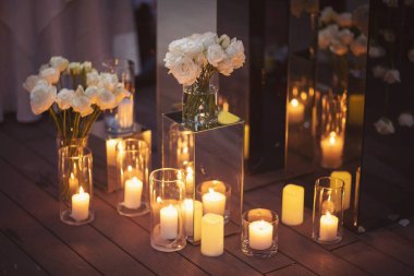 Zarif, geniş beyaz çiçekler ve düğün partisi için mumlar. Açık havada düğün seremonisi. Lüks ve güzel bir düğün dekoru. Akşam ışıklarıyla dekorasyon ayrıntıları.