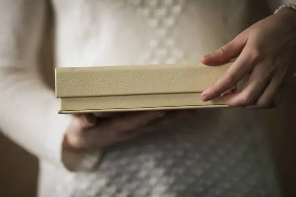 a woman opens a beige leather box for photo book. Woman hands holding and opening brown box. Present, packaging, shopping, delivery concept. shipping and home delivery. Surprise.