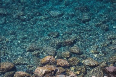 Durgun turkuaz deniz suyu ve insansız hava aracının erimiş lavlarından gelen kayaların havadan görünüşü. Deniz yüzeyi ve kayalık kıyı deseni. Liguria, İtalya. Ligurya denizinin turkuaz suyu.