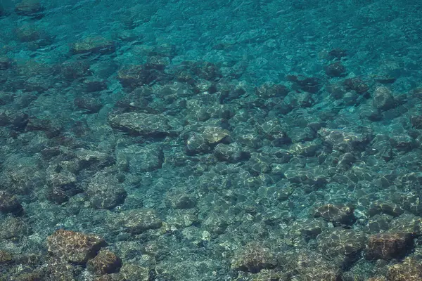 Durgun turkuaz deniz suyu ve insansız hava aracının erimiş lavlarından gelen kayaların havadan görünüşü. Deniz yüzeyi ve kayalık kıyı deseni. Liguria, İtalya. Ligurya denizinin turkuaz suyu.