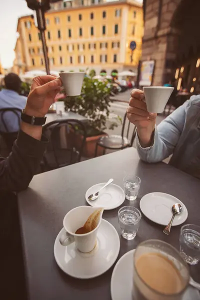 friends hands holding cups of coffee on wooden table in the street of Italy. Female hands hold a coffee cup. Coffee break.