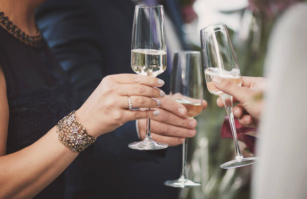 People having party with champagne cheers. Hands holding the glasses of champagne making a toast. 