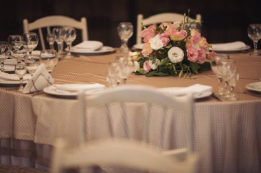 Düğün günü masada güzel çiçekler. Masa dekorunda çiçek masa numaraları ve mumlar var. Ayarlanmış masada bir demet çiçek.. 