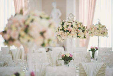 Düğün günü masada güzel çiçekler. Masa dekorunda çiçek masa numaraları ve mumlar var. Ayarlanmış masada bir demet çiçek.. 