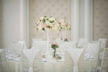 Düğün günü masada güzel çiçekler. Masa dekorunda çiçek masa numaraları ve mumlar var. Ayarlanmış masada bir demet çiçek.. 