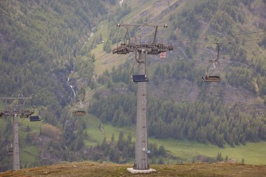 Biri yokuş aşağı giderken diğeri yokuş yukarı giden bir teleferik. Dağ yamacındaki teleferik kablosu. Dağlardaki gözetleme noktalarına kablolu araba gezisi. Turistler güzel manzaralardan hoşlanır..