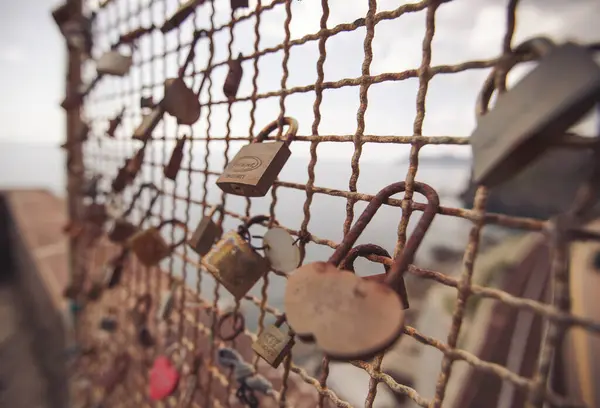 Thousands of lockers on a bridge symbolizing endless love, cinque terre, Italy. Padlocks as signs of love with dates attached to a foot-bridge. different colored padlocks chained to a rusty fence.