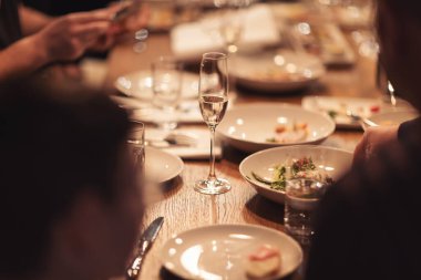 Birlikte yemek yiyen insanlar. Lüks, modern restarAunt 'da akşam ziyafeti veriyordu. Bir grup farklı arkadaş yemek yiyor. Şarap kadehleri ve abur cuburlarla dolu restoran masası..