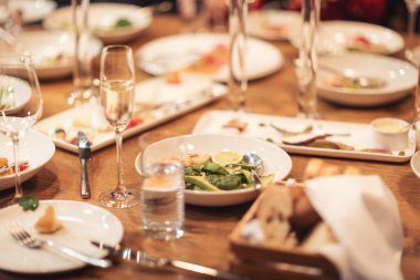 Birlikte yemek yiyen insanlar. Lüks, modern restarAunt 'da akşam ziyafeti veriyordu. Bir grup farklı arkadaş yemek yiyor. Şarap kadehleri ve abur cuburlarla dolu restoran masası..